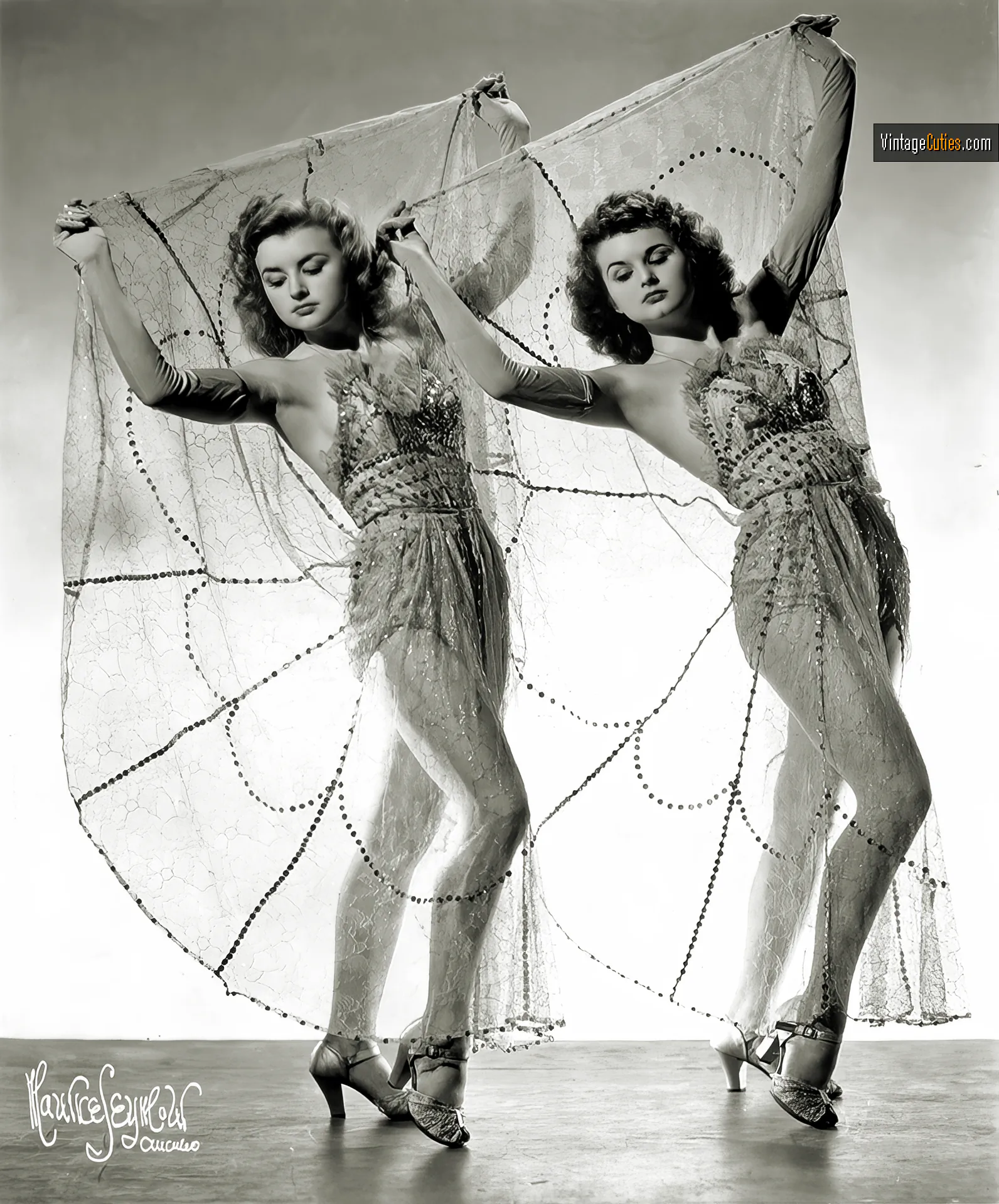Two curly vintage ladies in burlesque dresses pose identically
