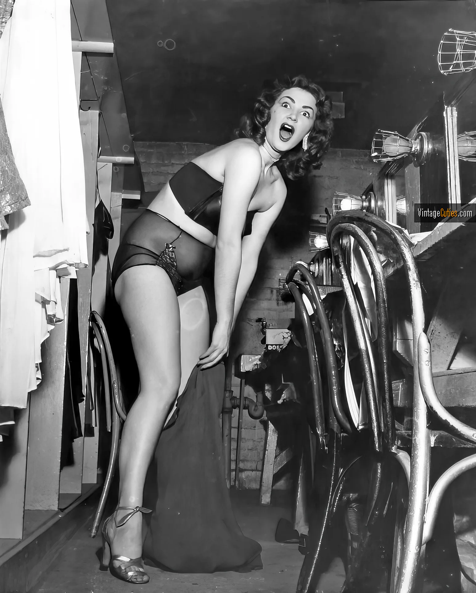 Surprised vintage burlesque dancer tries to put on her clothes